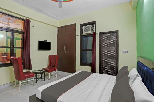 Un dormitorio con una cama y dos sillas rojas. en Hotel O Mango Bloom, en Noida