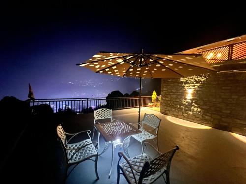 a patio with a table and chairs under an umbrella at The Hobbit Home, Bhimtal in Bhīm Tāl