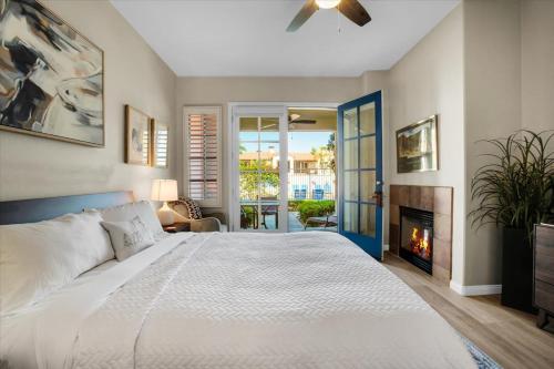 a bedroom with a white bed and a fireplace at Modern LQ 3BR Getaway Steps to pool & spa in La Quinta