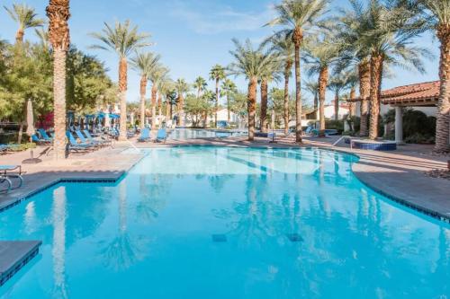 a swimming pool at a resort with palm trees at Desert Oasis Villa #A Steps from Pool in La Quinta