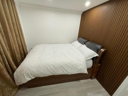 a small bedroom with a bed with white sheets at Vancouver Place in Orpington