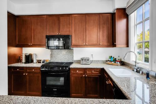 a kitchen with wooden cabinets and a black stove at Remodeled Desert Hideaway #A in La Quinta