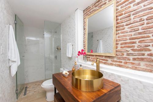 ein Badezimmer mit einem goldenen Waschbecken und einer Ziegelwand in der Unterkunft Villas La Fontana Amplias ApartaSuite-Piscina 203 in Panama-Stadt