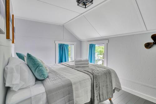 a white bedroom with a bed with blue pillows at Lakeside Retreat in Orono, Maine in Orono