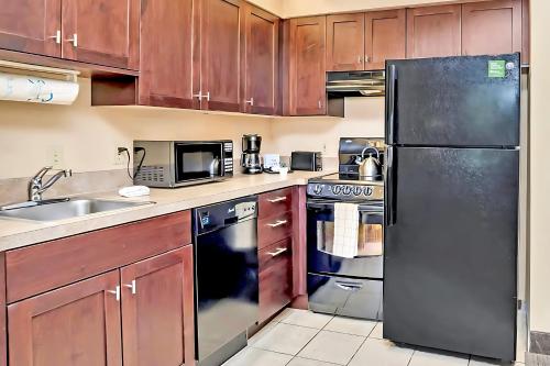 a kitchen with wooden cabinets and a black refrigerator at Contemporary Apartment with Pool Hot Tub - Close to Universal Studios in Orlando