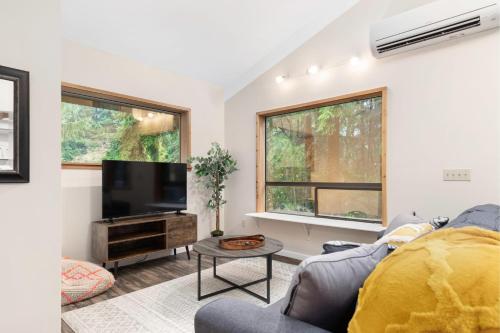 a living room with a couch and a tv at Perch - Rhododendron Loft in Coupeville