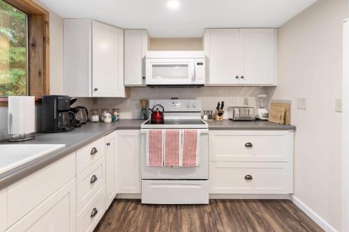 a kitchen with white cabinets and a stove top oven at Perch - Rhododendron Loft in Coupeville
