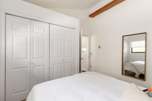 a white bedroom with a bed and a mirror at Perch - Rhododendron Loft in Coupeville