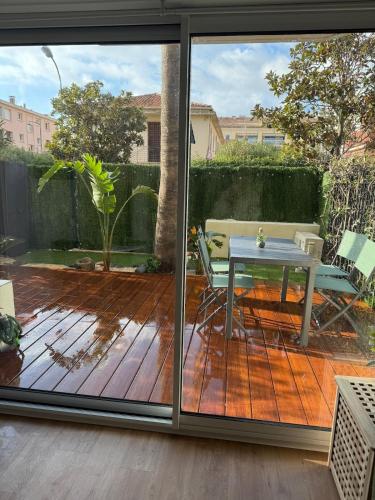 une porte coulissante en verre montrant un patio avec une table dans l'établissement Appart l 'Amaryllis, à Sanary-sur-Mer