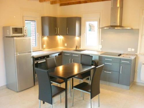 une cuisine avec une table, des chaises et un réfrigérateur dans l'établissement Gîte paisible avec jardin, WIFI et animaux acceptés - FR-1-510-228, à Flêtre