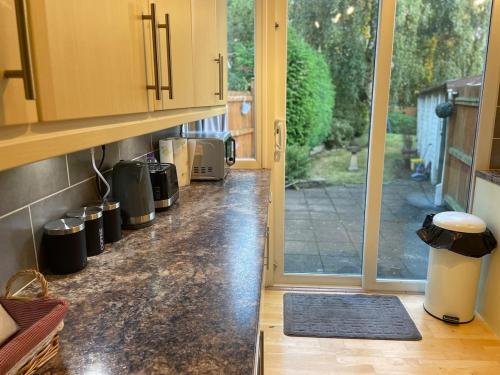 a kitchen with a counter top with a door to a yard at Beautiful 2 Bedroom house with big Garden & Parking fast wifi, and king size bed in Birmingham
