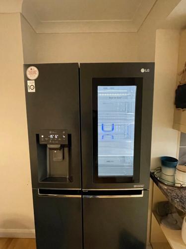 a black refrigerator with a window in a kitchen at Beautiful 2 Bedroom house with big Garden & Parking fast wifi, and king size bed in Birmingham