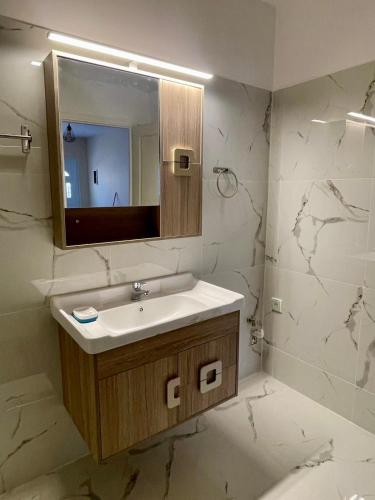 a bathroom with a sink and a mirror at Ivory Escape Apartment - ATH Airport in Spáta