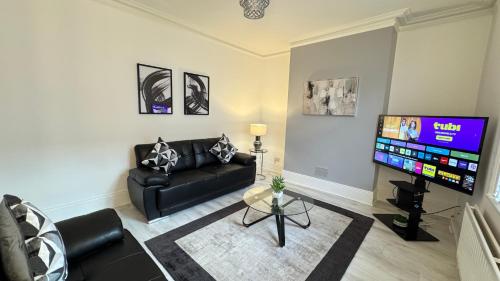 a living room with a couch and a flat screen tv at Sea Blue House, Cullercoats in Cullercoats