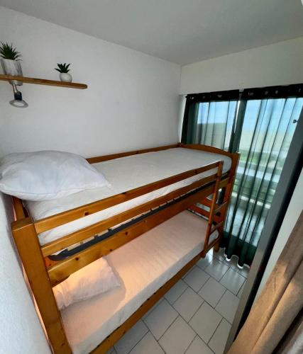 Ce lit superposé se trouve dans un dortoir doté d'une fenêtre. dans l'établissement Le Balcon Des Vagues, à Canet