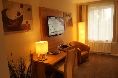 a living room with a desk and a chair and a television at Landhotel Klempau in Lübeck