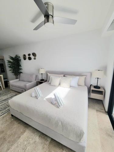 a white bedroom with a white bed and a couch at Condo en el corazon de Playa del Carmen in Playa del Carmen