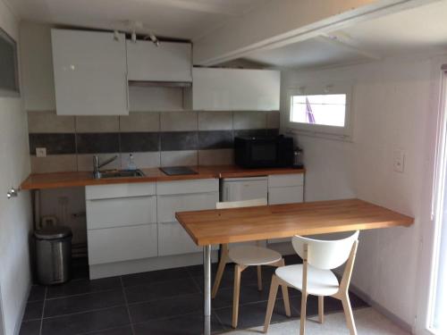 - une petite cuisine avec une table en bois et des placards blancs dans l'établissement Studio terrasse hyper center, à Avignon