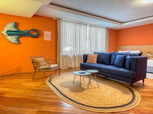 a living room with a blue couch and an orange wall at Hotel Boutique Casa Alebrije in Mexico City