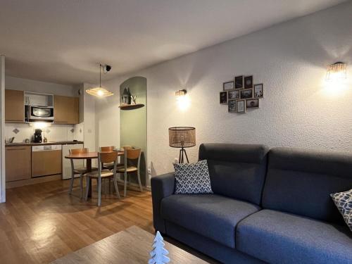 un salon avec un canapé bleu et une cuisine dans l'établissement Résidence Le Pic du Midi - maeva Home - Appartement 2 Pièces 4 personnes - Confort MAE-7631, à La Mongie