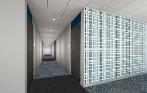 a corridor of a hallway with a white tile wall at Microtel Inn & Suites by Wyndham Olive Branch in Olive Branch
