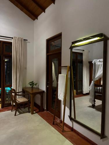 a mirror in a room with a table and a chair at The Lush Unawatuna in Unawatuna