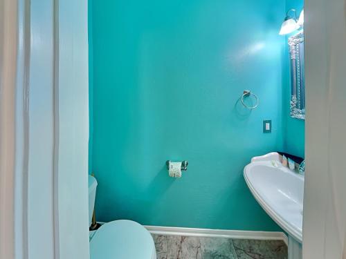 a blue bathroom with a toilet and a sink at Bishops Beach in Galveston