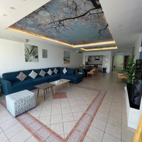 a living room with a blue couch and a table at شقة لافونتين الفندقي في شاطئ البرادايس - للعائلات فقط in Durat  Alarous