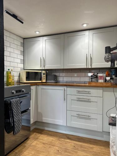 a kitchen with white cabinets and stainless steel appliances at 2BDR Cottage By Guest Nest Management In Horsham With Free Parking in Horsham