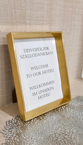 a sign in a frame on a table at Hotel Három Gúnár in Kecskemét