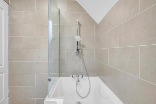 a bathroom with a bath tub and a shower at 3 Bedrooms Homely House in Motherwell Sleeps 8 comfortably with 6 double beds Near Glasgow Edinburgh Free Private Parking Business Travellers Contractors Holiday Goers Near all Major transport links in Carfin