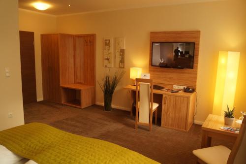 a bedroom with a bed and a desk with a television at Landhotel Klempau in Lübeck