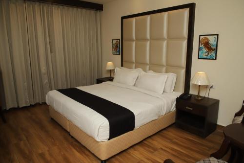 a bedroom with a large bed with a large headboard at Aar Kay Inn & Suites in Jalandhar