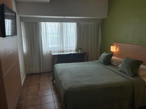 a hotel room with a bed and a desk and a window at Hotel Barramares in Recife