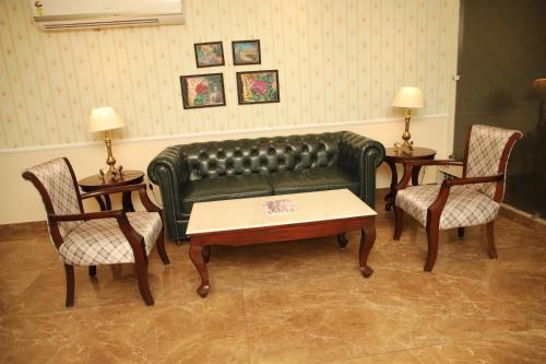 a living room with a green leather couch and two chairs at Aar Kay Inn & Suites in Jalandhar