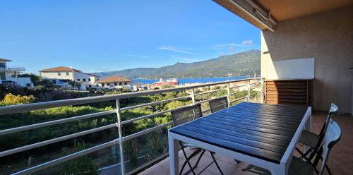 un balcon avec une table et une vue sur l'océan dans l'établissement Beau T3 Central - Vue mer & Piscine - A Funtana, à Propriano