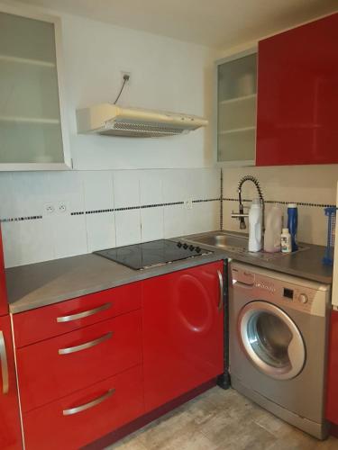- une cuisine avec des placards rouges et un lave-linge dans l'établissement 2 pièces sans voisin, à Schiltigheim