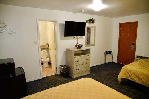 a hotel room with a bedroom with a tv on the wall at El Camino Motel in Tallahassee