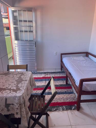 a bedroom with a bed and a table and a rug at Vivendas Raízes do forte in Praia do Forte
