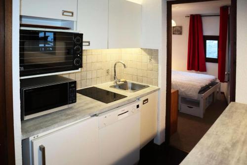 une petite cuisine avec un évier et un micro-ondes dans l'établissement Résidence Le Cairn - Résidence Cairn - appartement T2 6 personnes MAE-6311, aux Orres