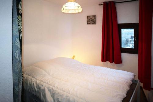 - une chambre avec un lit blanc et un rideau rouge dans l'établissement Résidence Le Cairn - Résidence Cairn - appartement T2 6 personnes MAE-6311, aux Orres