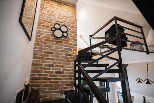 a spiral staircase next to a brick wall with a clock at Promenada Apartmani Zlatibor in Zlatibor