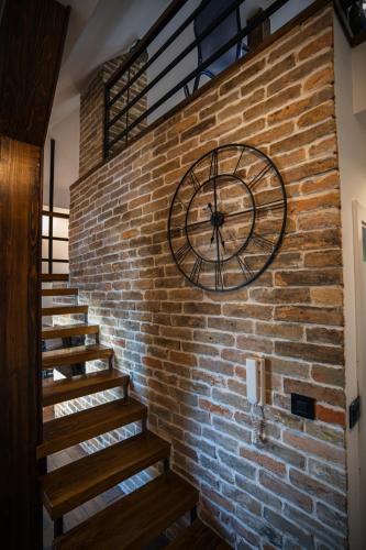 a large clock on a brick wall with stairs at Promenada Apartmani Zlatibor in Zlatibor