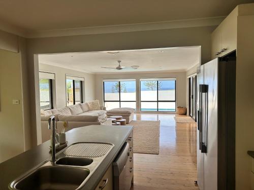 a kitchen with a sink and a living room at Astéri by the Sea in Gerroa