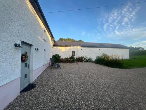 a white building with a door and a gravel driveway at The Farmhouse in Spinans Cross Roads