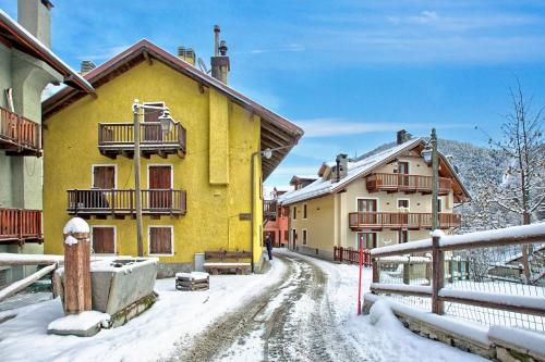 a yellow house on a snow covered street at Appartamento La Fontaine Ski In Ski Out - Happy Rentals in Claviere