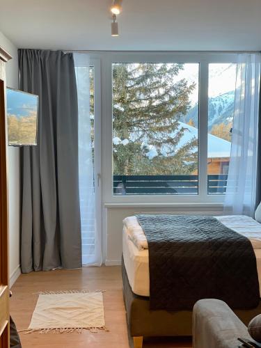 a bedroom with a bed and a large window at NEST'L Appartements & Zimmer in Mösern