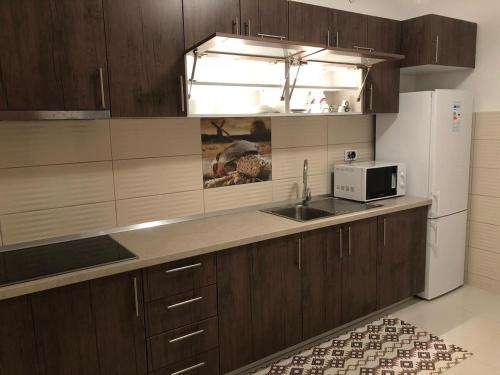 a kitchen with wooden cabinets and a sink and a refrigerator at Sweet family home in Doglodi