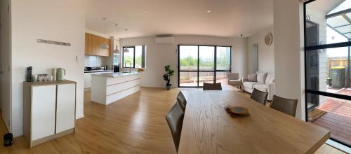 a kitchen and a living room with a wooden table at CozyNest0 in Auckland