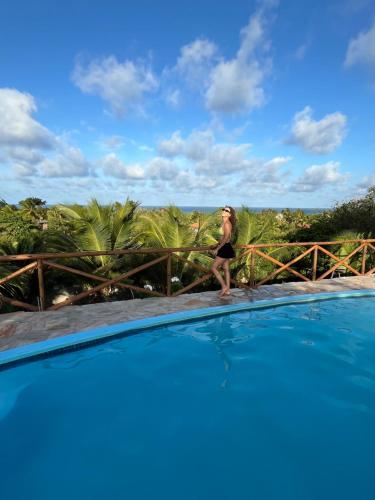 a woman is standing next to a swimming pool at Pipa Golfinhos Pousada in Pipa